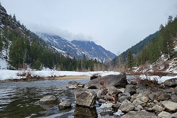 A river with rocks in the foreground and mountains in the background