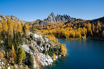 A lake surrounded by woods with a mountain in the distance