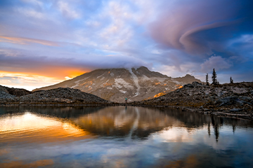 A mountain covered in clouds looming over a lake