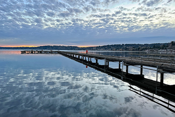 A dock stretching out to the distance, with a clouded sky in the background