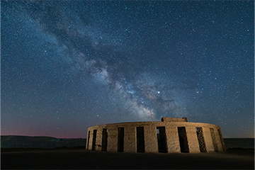 A monument of stone pillars set dramatically in the foreground of a starlit sky