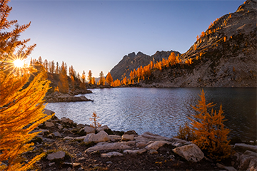 A lake surrounded by orange trees and mountains