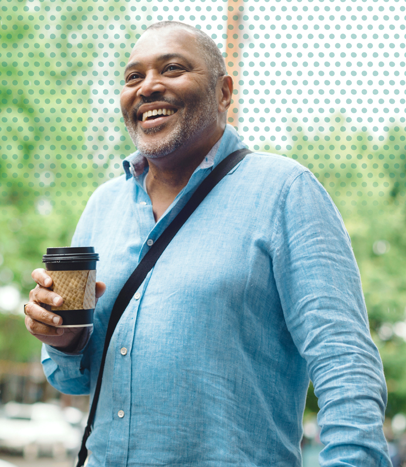 A man holding a to-go coffee cup, smiling