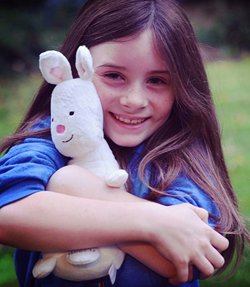 A young girl hugs a WSECU Munny Bunny stuffed animal