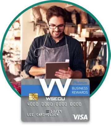 Store owner in apron holding tablet. Image of WSECU Platinum Business Rewards Visa card below. 