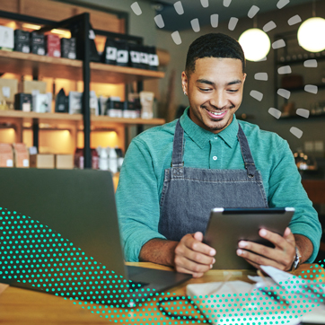 a man behind a counter in a storelooks at a tablet