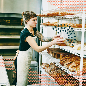 Store owner in apron arranging breads on a shelf