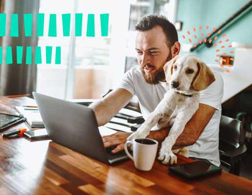 A dog sitting on the lap of a man working in front of a computer