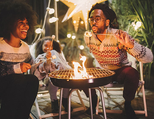 couple sitting around fire roasting marshmallows on a patio