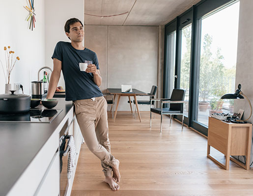 man standing at kitchen counter with coffee cup