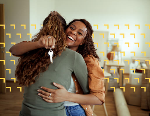 a couple embracing while one of them holds the keys to their new house