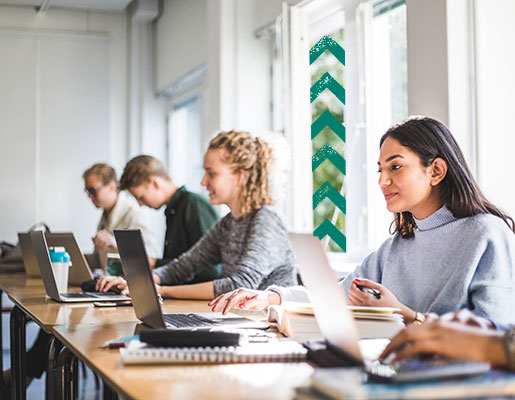 students sitting in class using laptops