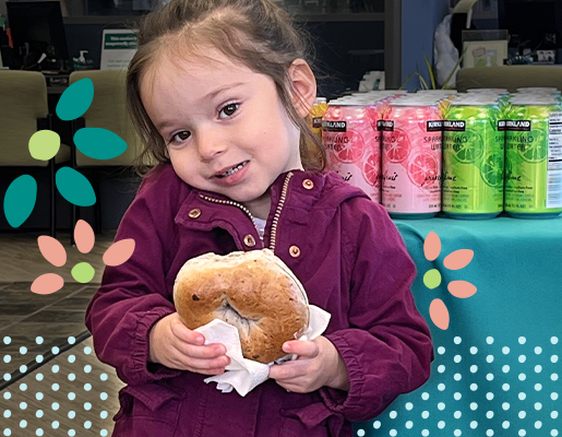 Child holding a bagel, smiling