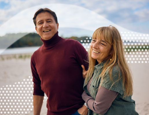 Beach setting showing two people in casual clothing with a natural landscape in the background.