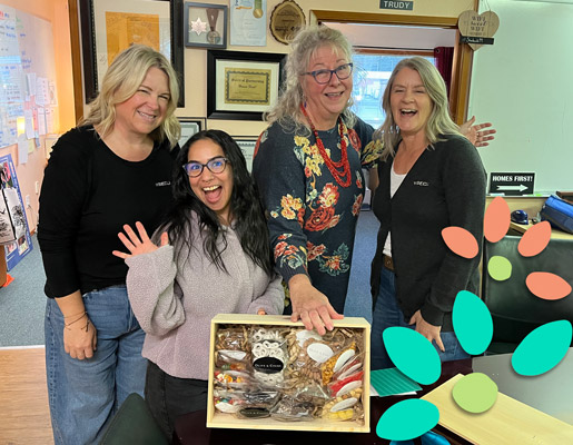 Four people in an office environment showing a gift box with different wrapped treats.