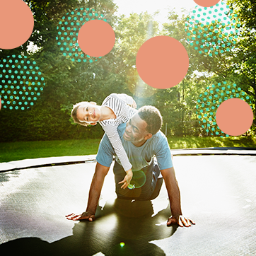 A father playing on a trampoline with his son