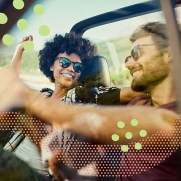 A couple wearing shades, smiling while driving