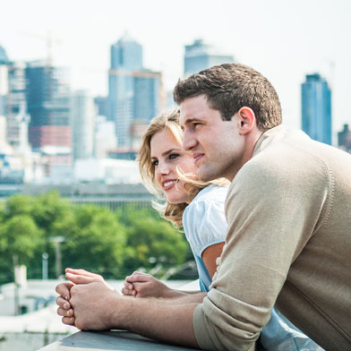 Man and woman leaning on edge of building