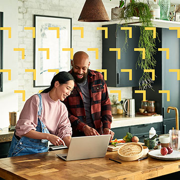 A couple looking at a laptop on the kitchen counter