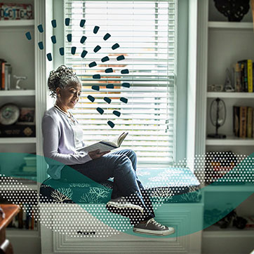 A person reading a book by a window nook