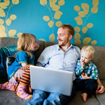 A parent with two children looking at a laptop