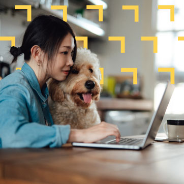 A woman with her dog looking at a laptop on a table