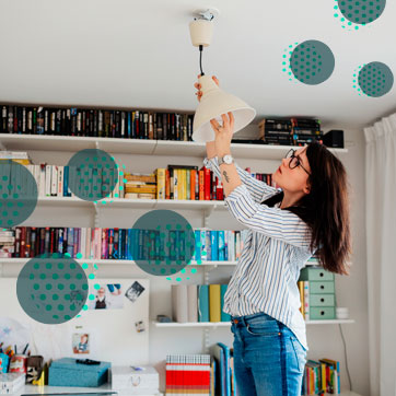 Woman fixing a light bulb on a ceiling lamp
