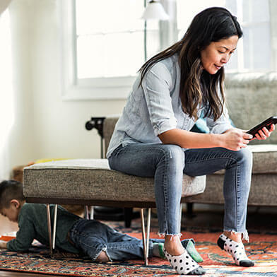 Woman looking at cell phone while child is playing