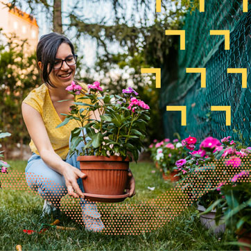 A woman placing a potted flower by her fence.