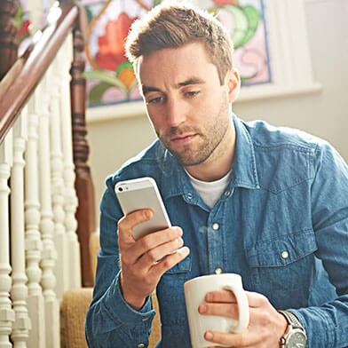 Man drinking coffee while looking at phone