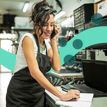 a woman in a kitchen on the phone while she takes notes in a notebook