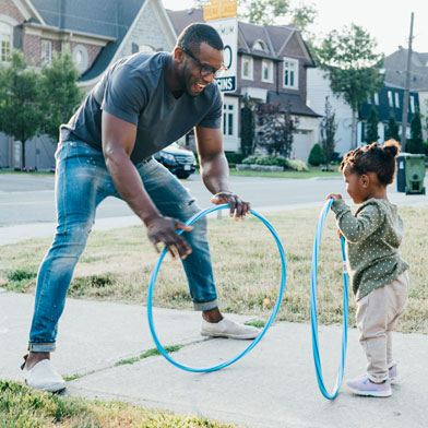 a dad playing with his daughter in the driveway