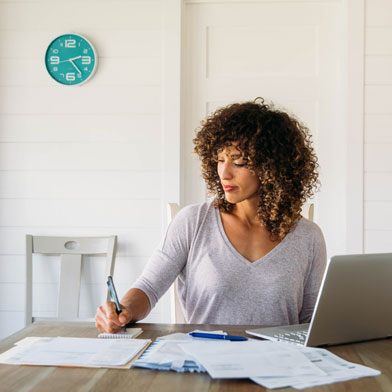 woman taking notes of things from a laptop