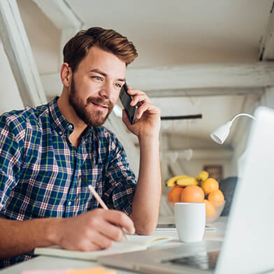 Man talking on cellphone while sitting at laptop