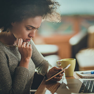 Woman looking at cell phone while sitting at a table