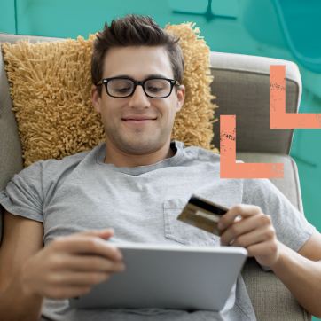 Man sitting on a couch with a credit card and tablet