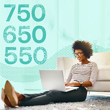 Woman looking at laptop while sitting on floor and leaning on a couch