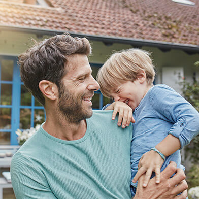 father holding son in front of a house