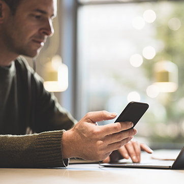 man sitting at a table with a phone and computer