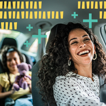 A woman smiling, while sitting on the driver seat of a car with a young girl sitting in the back seat holding a teddy bear.