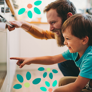 Father and son looking at an oven door, smiling