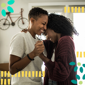 Two women standing in a slow dance position, smiling while holding hands