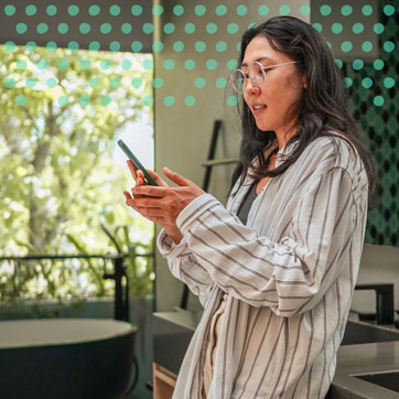 A woman leaning on the kitchen counter, looking at her phone