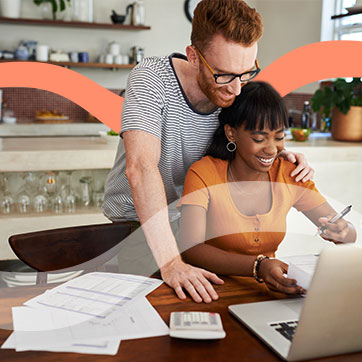 Couple looking through paperwork in front of a laptop on the dining room table