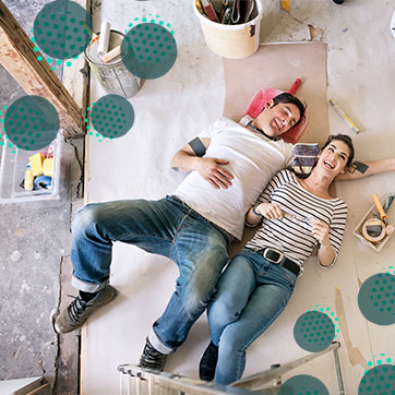 Couple lying on the floor covered with paper, surrounded by painting materials