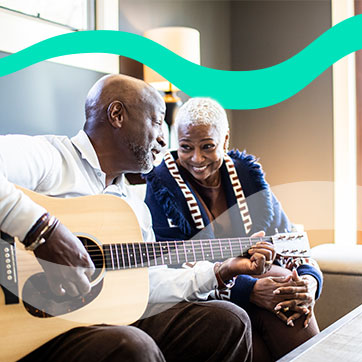 Woman smiling at her husband while he plays the guitar