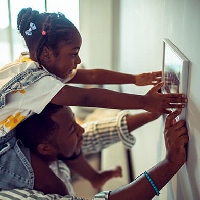 Father and daughter hanging up a picture