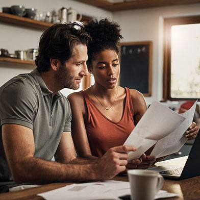 a couple comparing a stack of mortgage papers