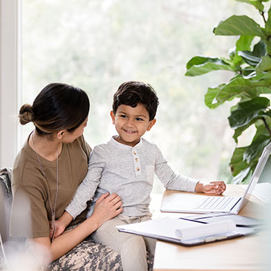 a woman sitting at a desk with her son on her lap