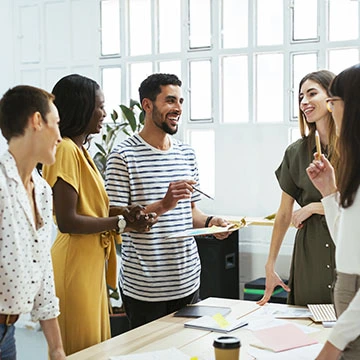 People standing around a clipboard in a meeting